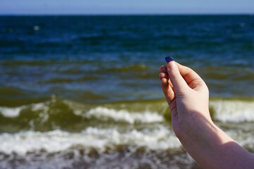 Child's hand with sea glass on the sea background.