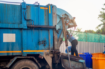 Garbage collector on the garbage truck.Sweeper or Worker are loading waste into the garbage truck...