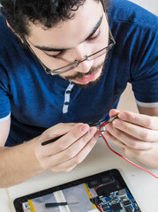 computer repairman repairing components of electronic device. young man repairs a tablet.