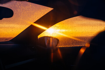Sunset through the car windshield, rain drops on the glass 