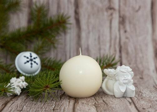 On a wooden background, an unlit candle, spruce branches and an angel waiting for the miracles of the Nativity.