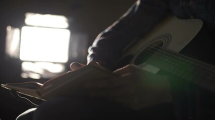 Man plays the guitar, stops and writes text or notes in a notebook