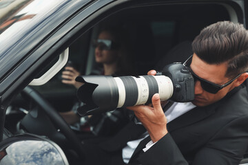 Fototapeta Private detectives with modern camera spying from car obraz