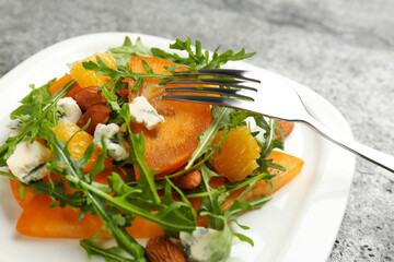 Delicious persimmon salad served on grey table, closeup
