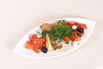 Slices of red fish on a plate with olives, lemon, dill and white sauce