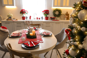 Table with dishware in beautiful kitchen interior decorated for Christmas