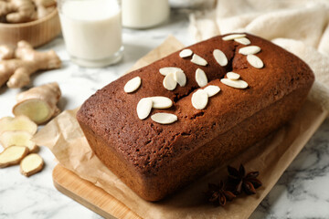 Fototapeta na wymiar Delicious gingerbread cake with almond petals on white marble table