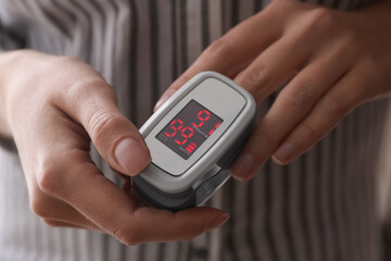 Woman measuring oxygen level with modern fingertip pulse oximeter, closeup