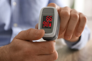 Man measuring oxygen level with modern fingertip pulse oximeter, closeup