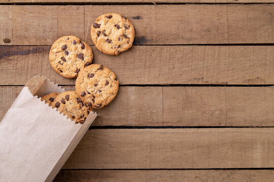 Chocolate chip cookies on a paper bag over a wooden table with copy space