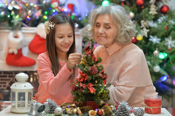 Smiling little girl with grandmother preparing for Christmas