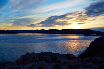 Beautiful sunrise on the frozen lake Baikal. Winter landscape in Russia. Endless expanses transparent smooth ice with cracks.