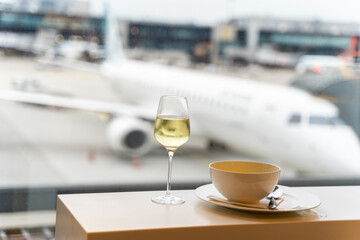 Glass of wine, bowl of soup near window with a view to airplane in airport