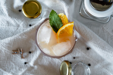 Top down view of cocktail with ice cubes and fresh mint and orange decoration
