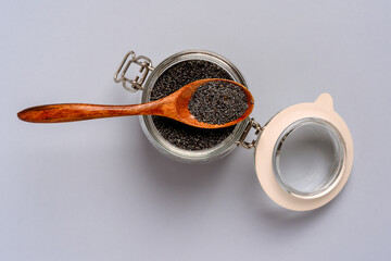 Dry poppy seeds in a glass jar on a blue background