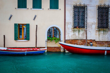 Fototapeta na wymiar Boats and ancient houses in the channels of Venice, Venetian, Italy