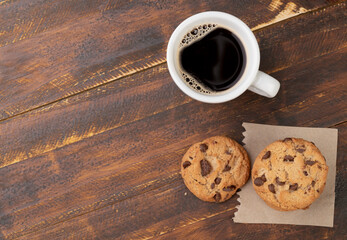 Chocolate chip cookies and coffee over wooden table with copy space