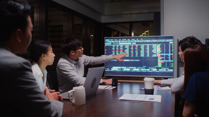 Young Asian businessman lead group of business financial team in strategic meeting presentation, work late night in office. Marketing strategy analysis, stock market trading, or corporate teamwork © Urbanscape