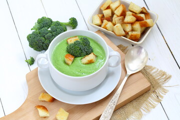 Soup puree with broccoli in white soup stock on a wooden background
