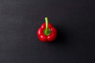 Red bell pepper lies on a black background. Flat lay, top view
