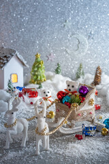 Christmas fabulous composition. Polar bear in a Christmas sleigh with gifts and toys on the background of houses and fir trees in the snow