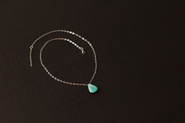 Pendant made of natural turquoise on a silver chain on a black background. Jewelry from natural stones