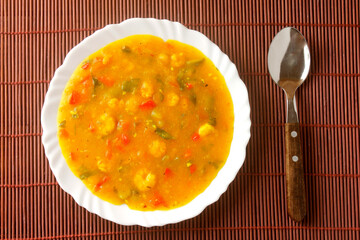 Pirão is a traditional dish of Brazilian cuisine made from cassava flour, fish or shrimp, on a plate on a rustic wooden table.