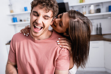 Smiling woman hugging excited man in kitchen