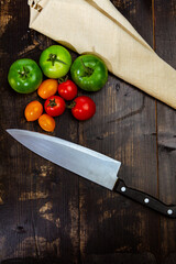 High angle shot of ripe and unripe tomatoes with knife and napkin on a wooden table