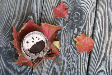 Marshmallow in a jar. With cookies and chocolate. Dried maple leaves. On pine boards.