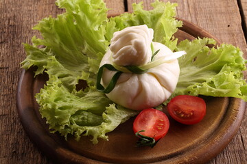 Burrata with tomatoes and cream on lettuce leaves