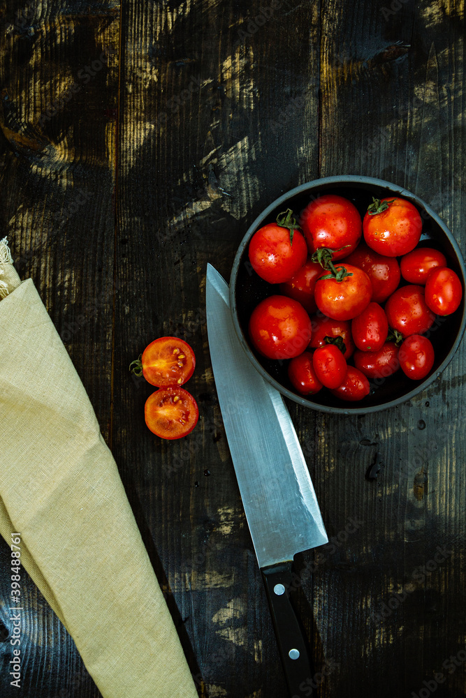 Sticker closeup shot of fresh red tomatoes on a bowl with a knife and napkin on a wooden table