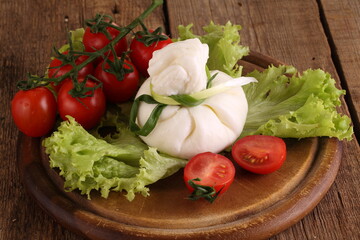 Burrata with tomatoes and cream on lettuce leaves