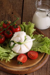 Burrata with tomatoes and cream on lettuce leaves