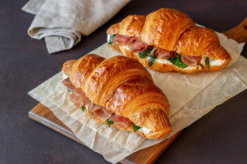 Croissants sandwiches with prosciutto, basil and white cheese. French cuisine. Breakfast.