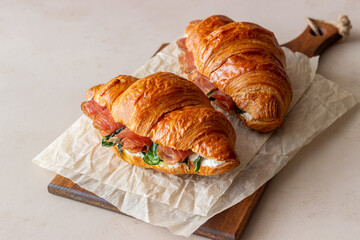 Croissants sandwiches with prosciutto, basil and white cheese. French cuisine. Breakfast.