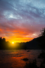 Beautiful sunset in mountains. Purple sky colours and clouds. Amazing reflection in river. Travelling concept. Perfect evening nature.