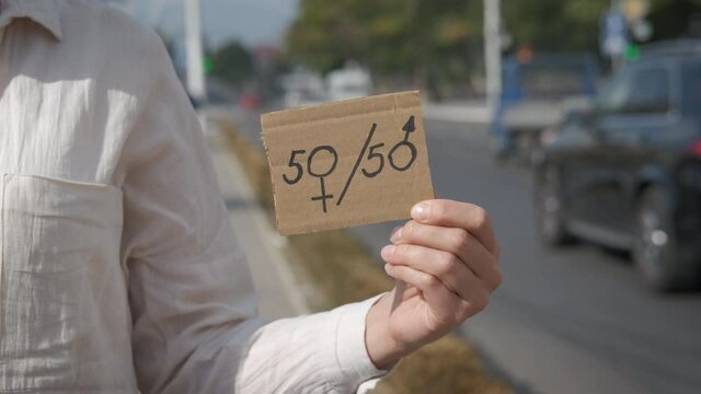 50 to 50. Equality of women. A woman in the city holding a 50-50 sign.