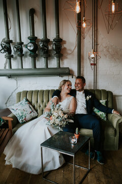 industrial wedding: bride and groom sitting on a vintage sofa.
