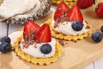 Mascarpone cheese with strawberries and blueberries on a white wooden table