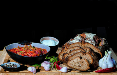 
On the table, Russian homemade borsch with homemade black bread. With sour cream and garlic.