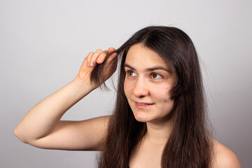 Fototapeta premium A woman is growing a long bang. Hair care, oils and vials for hair growth. Healthy brunette hair.