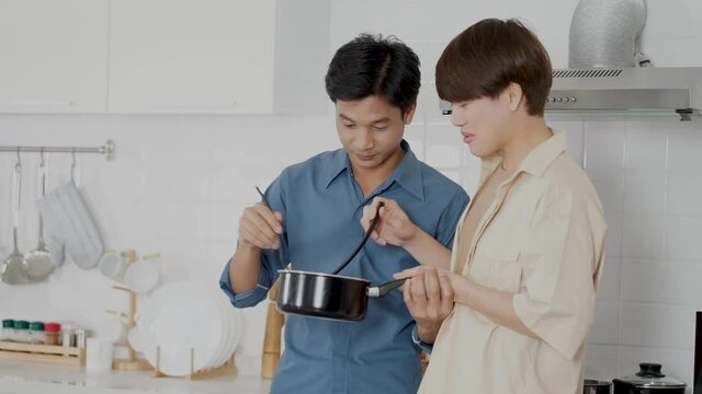 Asian Man Same Sex LGBTQ Couple Cooking Food In The Kitchen