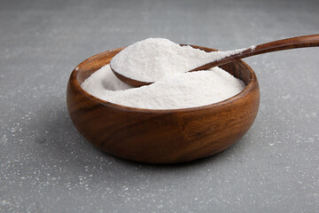 Closeup collagen powder in a wooden plate with a spoon or measuring quantity on concrete background. f Extra protein intake. Natural supplements for beauty.