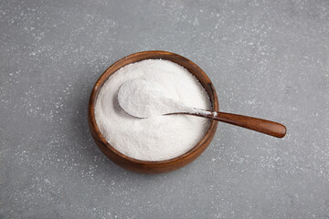 Closeup collagen powder in a wooden plate with a spoon or measuring quantity on concrete background. f Extra protein intake. Natural supplements for beauty.