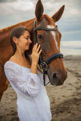 Obraz premium Portrait of beautiful woman and brown horse. Caucasian woman hugging and stroking horse. Love to animals. Beach in Bali, Indonesia