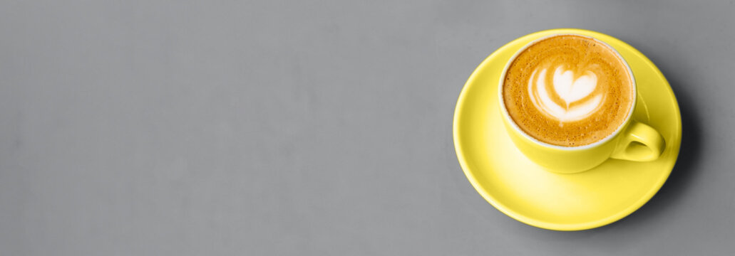 White cup of cappuccino with beautiful latte art on a table. Place for text. Shallow depth of field. Color 2021. Banner for website.