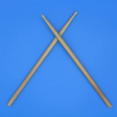 Crossed percussion drumsticks on a blue background.