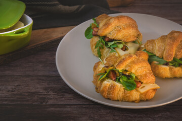 Three freshly baked butter croissants stuffed with fried onions, sausage, bacon, arugula and corn salad.