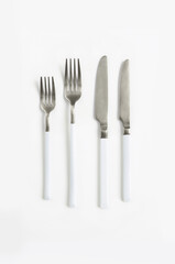 White silver or steel cutlery view from above on a white background. Top view..Knife and fork for a festive table for a wedding, birthday or party.